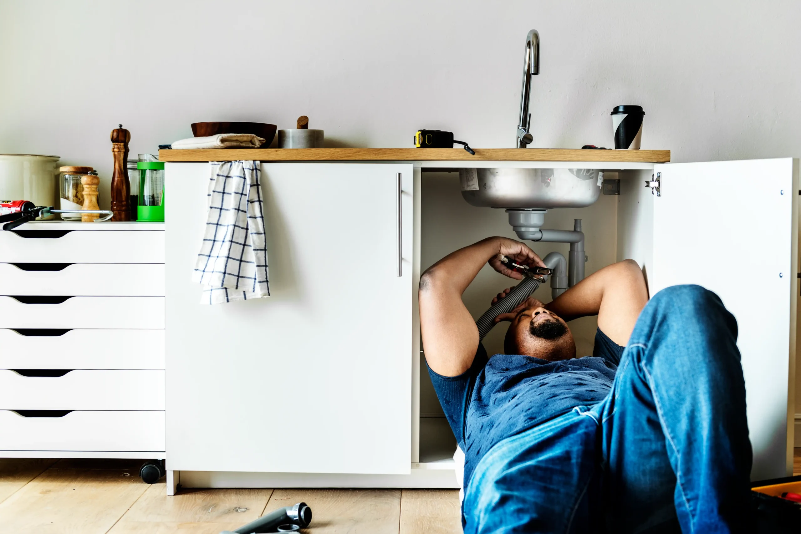 Plombier réalisant un débouchage Liège sous un évier de cuisine